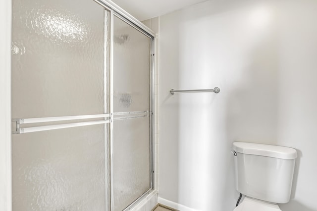 bathroom with a shower with shower door and toilet