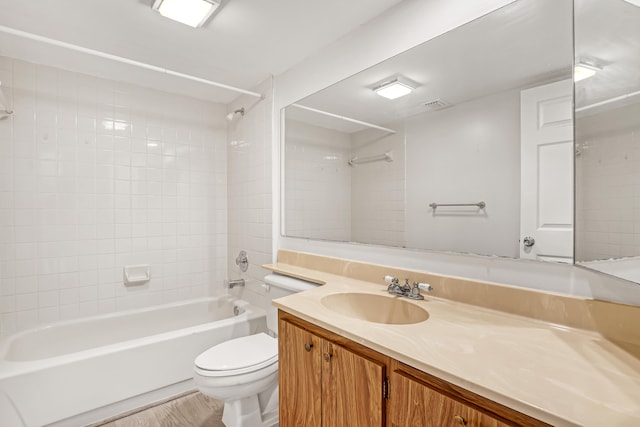 full bathroom featuring tiled shower / bath, hardwood / wood-style floors, vanity, and toilet