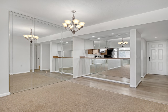 kitchen featuring stainless steel appliances, light hardwood / wood-style flooring, an inviting chandelier, white cabinets, and hanging light fixtures