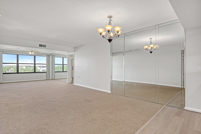 spare room featuring hardwood / wood-style floors and ceiling fan with notable chandelier