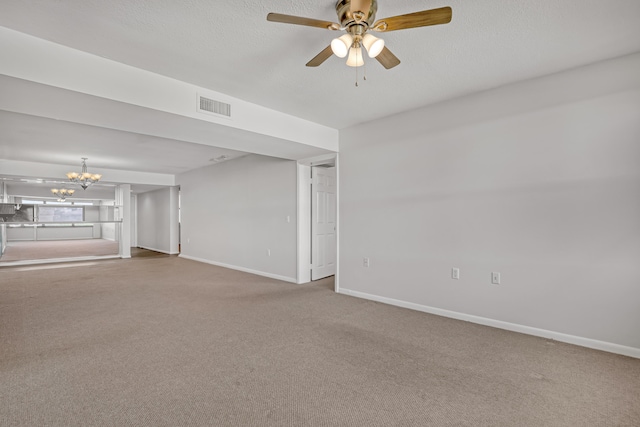 carpeted spare room with a textured ceiling and ceiling fan with notable chandelier