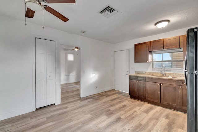 kitchen featuring stainless steel fridge, light wood-type flooring, a textured ceiling, ceiling fan, and sink