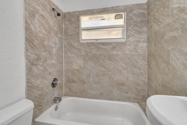 bathroom featuring toilet and tiled shower / bath