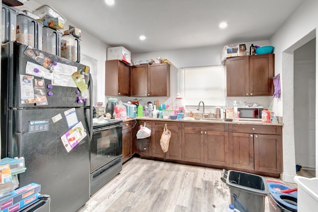 kitchen featuring black appliances, light hardwood / wood-style floors, and sink