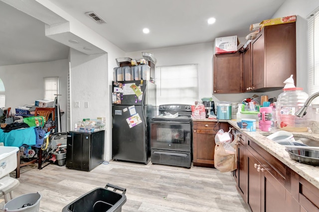 kitchen with light hardwood / wood-style flooring, stainless steel refrigerator, black electric range oven, and sink