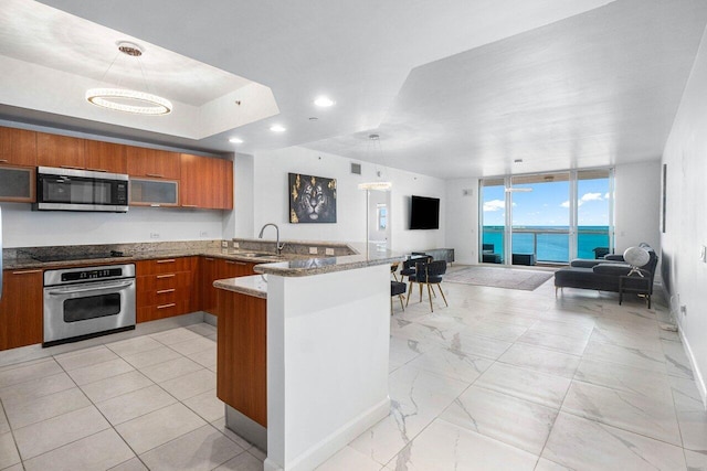 kitchen featuring kitchen peninsula, appliances with stainless steel finishes, hanging light fixtures, and sink