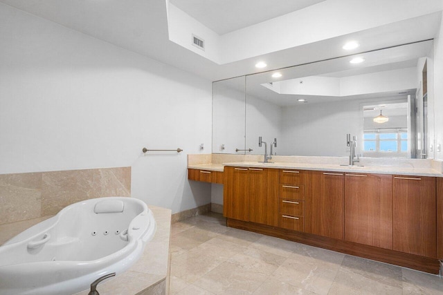 bathroom with tiled tub and vanity