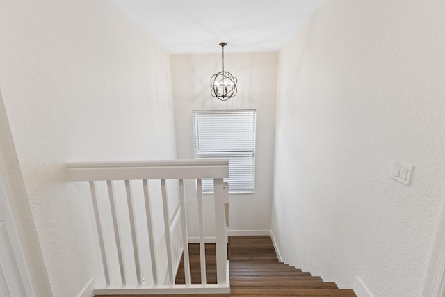 stairway featuring hardwood / wood-style floors and an inviting chandelier