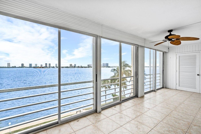 unfurnished sunroom featuring a wealth of natural light, a water view, and ceiling fan