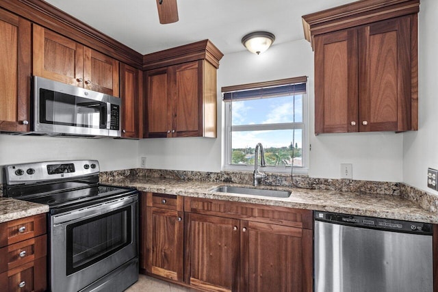 kitchen with ceiling fan, sink, stainless steel appliances, and dark stone counters