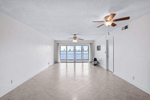 unfurnished room featuring ceiling fan, light tile patterned flooring, and a textured ceiling