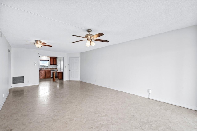 unfurnished living room featuring ceiling fan and a textured ceiling