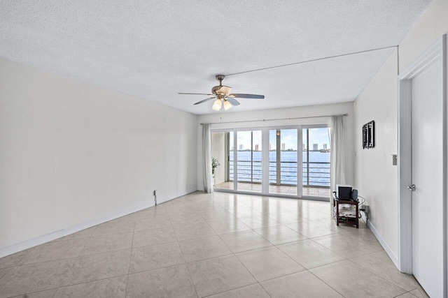 tiled empty room with ceiling fan and a textured ceiling