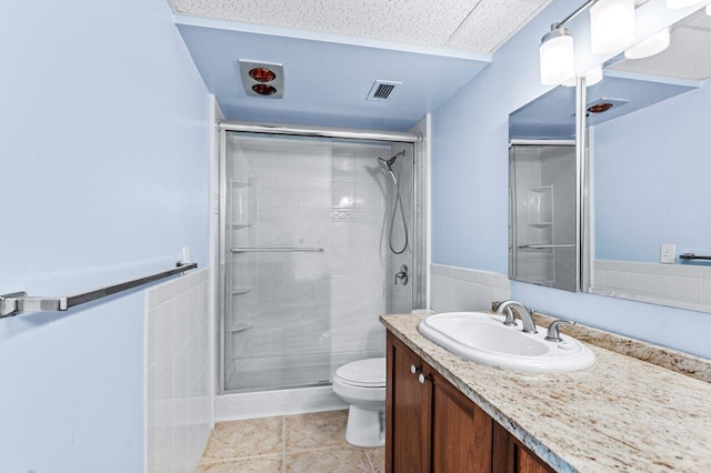 bathroom with tile walls, vanity, an enclosed shower, and toilet