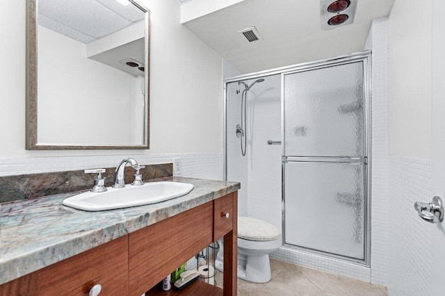 bathroom with tile patterned floors, vanity, toilet, and tile walls