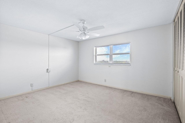 carpeted spare room featuring ceiling fan and a textured ceiling