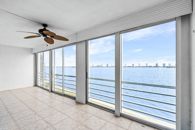 unfurnished sunroom featuring a water view and ceiling fan