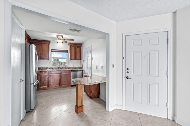 kitchen with light stone countertops, appliances with stainless steel finishes, a textured ceiling, ceiling fan, and sink