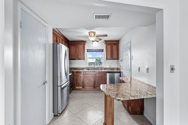 kitchen featuring light stone counters, stainless steel appliances, ceiling fan, sink, and light tile patterned floors