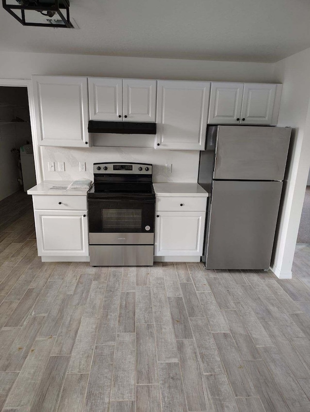 kitchen with light wood-type flooring, stainless steel appliances, and white cabinetry