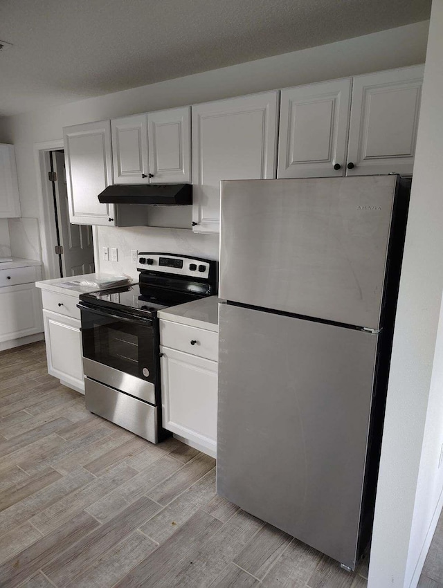 kitchen with backsplash, white cabinetry, light wood-type flooring, and appliances with stainless steel finishes