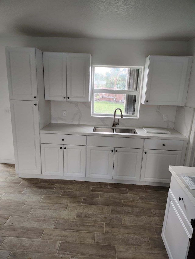 kitchen with white cabinets, wood-type flooring, a textured ceiling, and sink