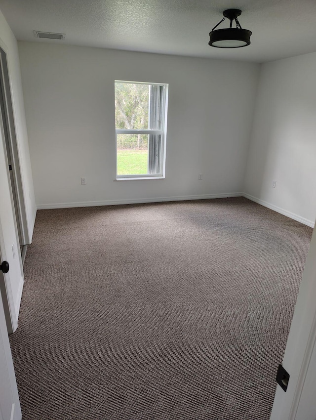 unfurnished room with dark colored carpet and a textured ceiling