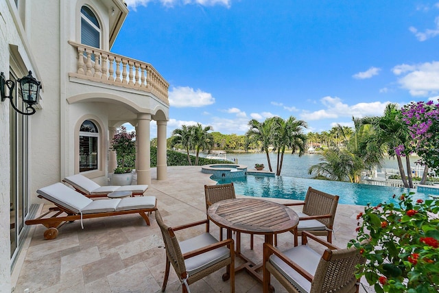 view of pool with an in ground hot tub, a patio, and a water view