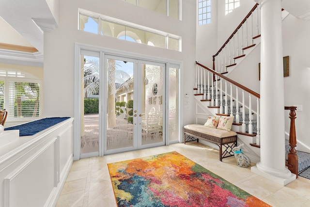 doorway to outside with french doors, light tile patterned floors, a healthy amount of sunlight, and a high ceiling