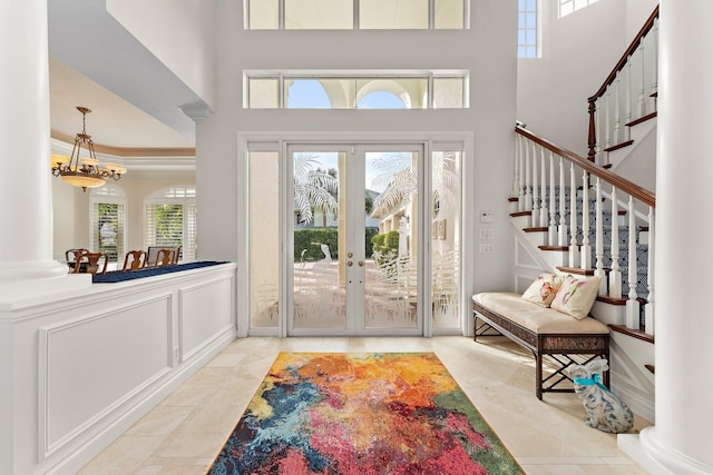 foyer entrance with a healthy amount of sunlight, crown molding, a high ceiling, and french doors