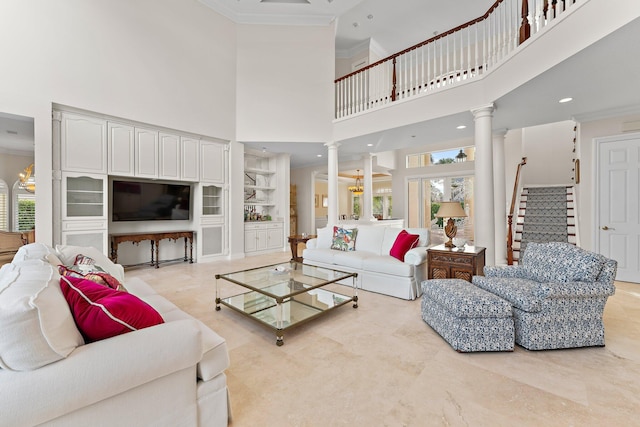 living room featuring ornate columns, a high ceiling, an inviting chandelier, built in features, and ornamental molding