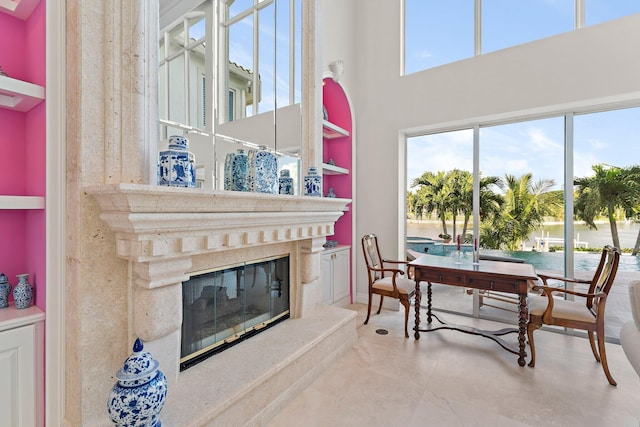 interior space with a water view, a towering ceiling, and a fireplace