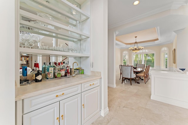 bar with white cabinetry, hanging light fixtures, ornamental molding, and sink