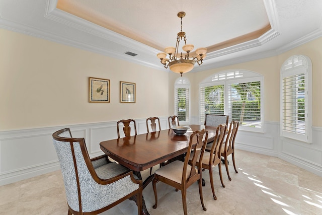 dining room with a tray ceiling, ornamental molding, and a notable chandelier