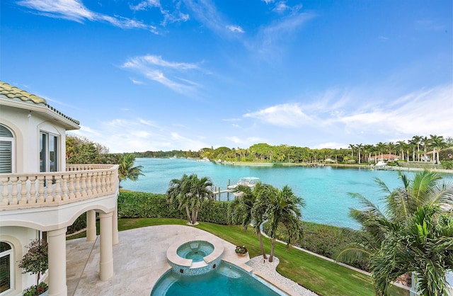 view of pool featuring an in ground hot tub, a water view, and a patio