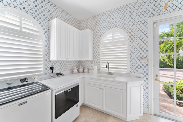 clothes washing area featuring cabinets, sink, light tile patterned floors, and washer and dryer