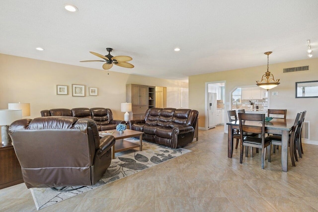 living room with ceiling fan and a textured ceiling