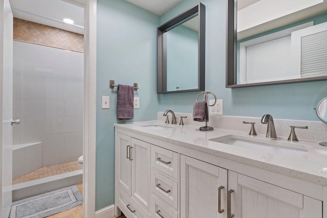 bathroom featuring vanity, toilet, and a tile shower