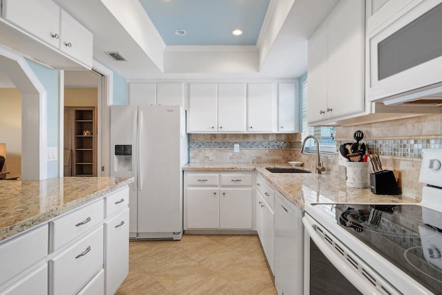 kitchen with white appliances, white cabinets, sink, decorative backsplash, and a tray ceiling