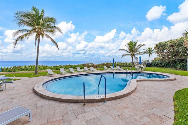 view of pool featuring a patio area and a water view