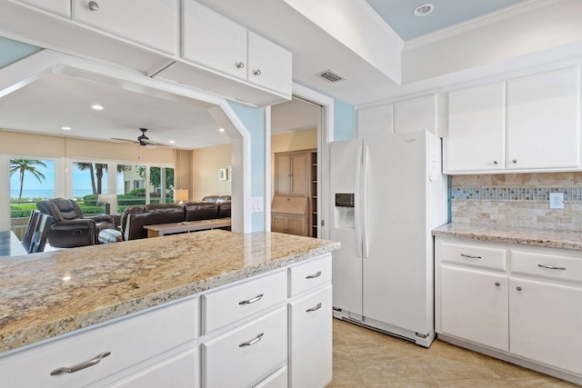 interior space featuring white cabinetry, light stone countertops, backsplash, white appliances, and light tile patterned flooring