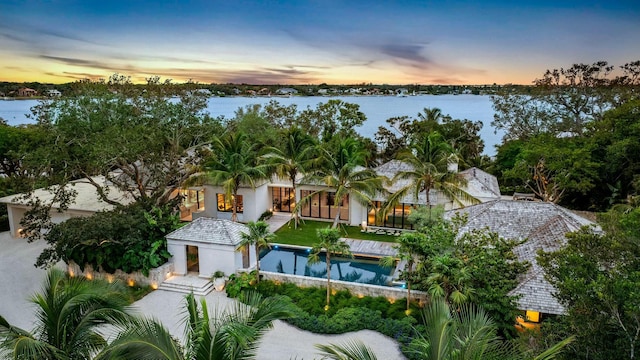 aerial view at dusk featuring a water view