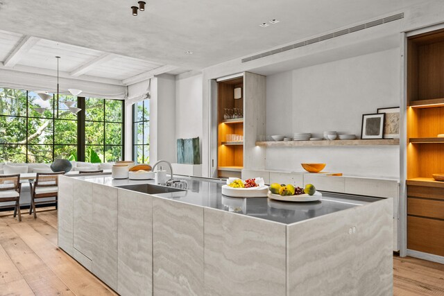 kitchen with decorative light fixtures, light hardwood / wood-style floors, coffered ceiling, and sink