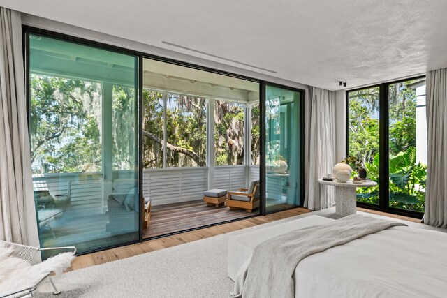 bedroom with hardwood / wood-style floors, access to exterior, and multiple windows