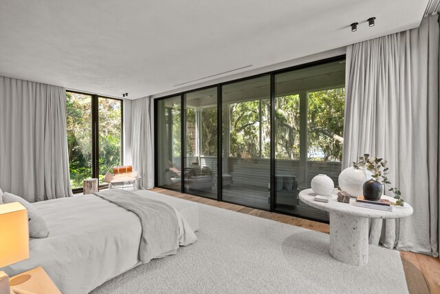 bedroom featuring floor to ceiling windows, wood-type flooring, and access to exterior