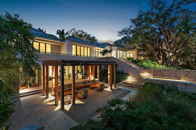 back house at dusk featuring outdoor lounge area and a wooden deck