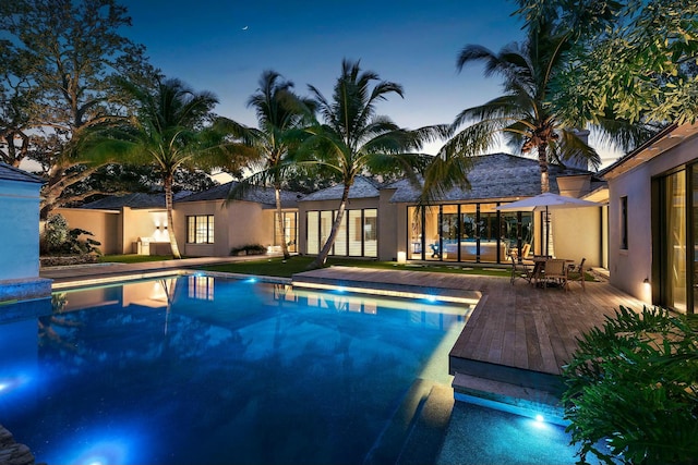 pool at dusk featuring a deck