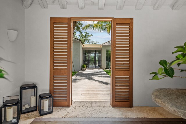 doorway to outside with beam ceiling