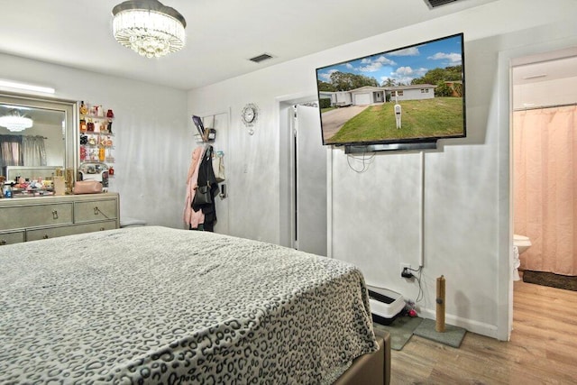 bedroom featuring connected bathroom and hardwood / wood-style flooring