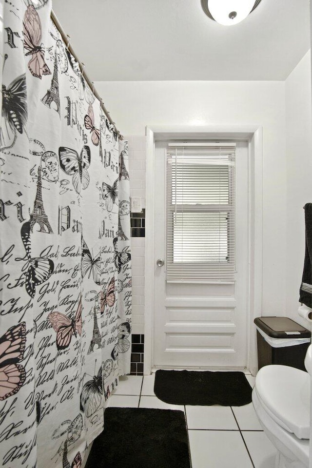 bathroom featuring tile patterned flooring, a shower with shower curtain, and toilet